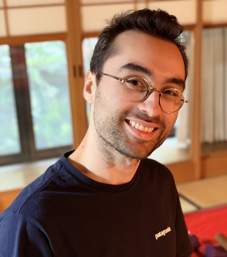 Samuel Privé smiling, wearing glasses and a dark shirt